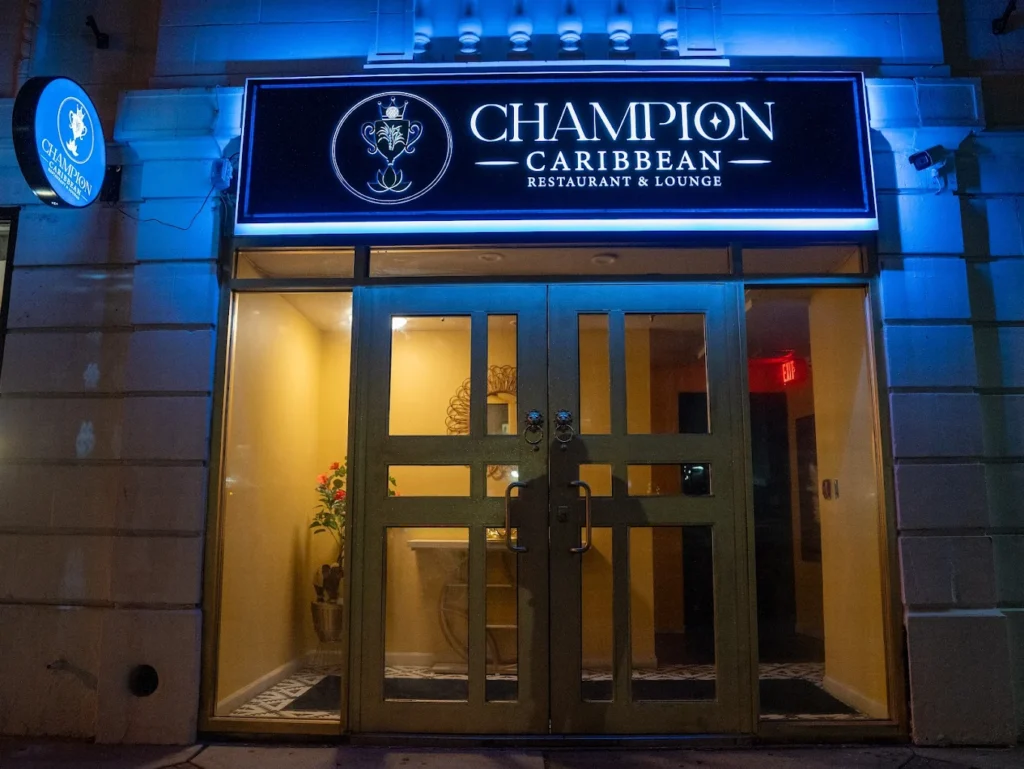 Champion Caribbean Restaurant and Lounge storefront with blue-lit signage at night