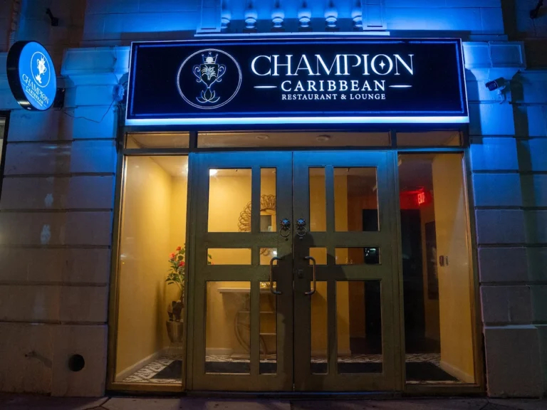 Champion Caribbean Restaurant and Lounge storefront with blue-lit signage at night